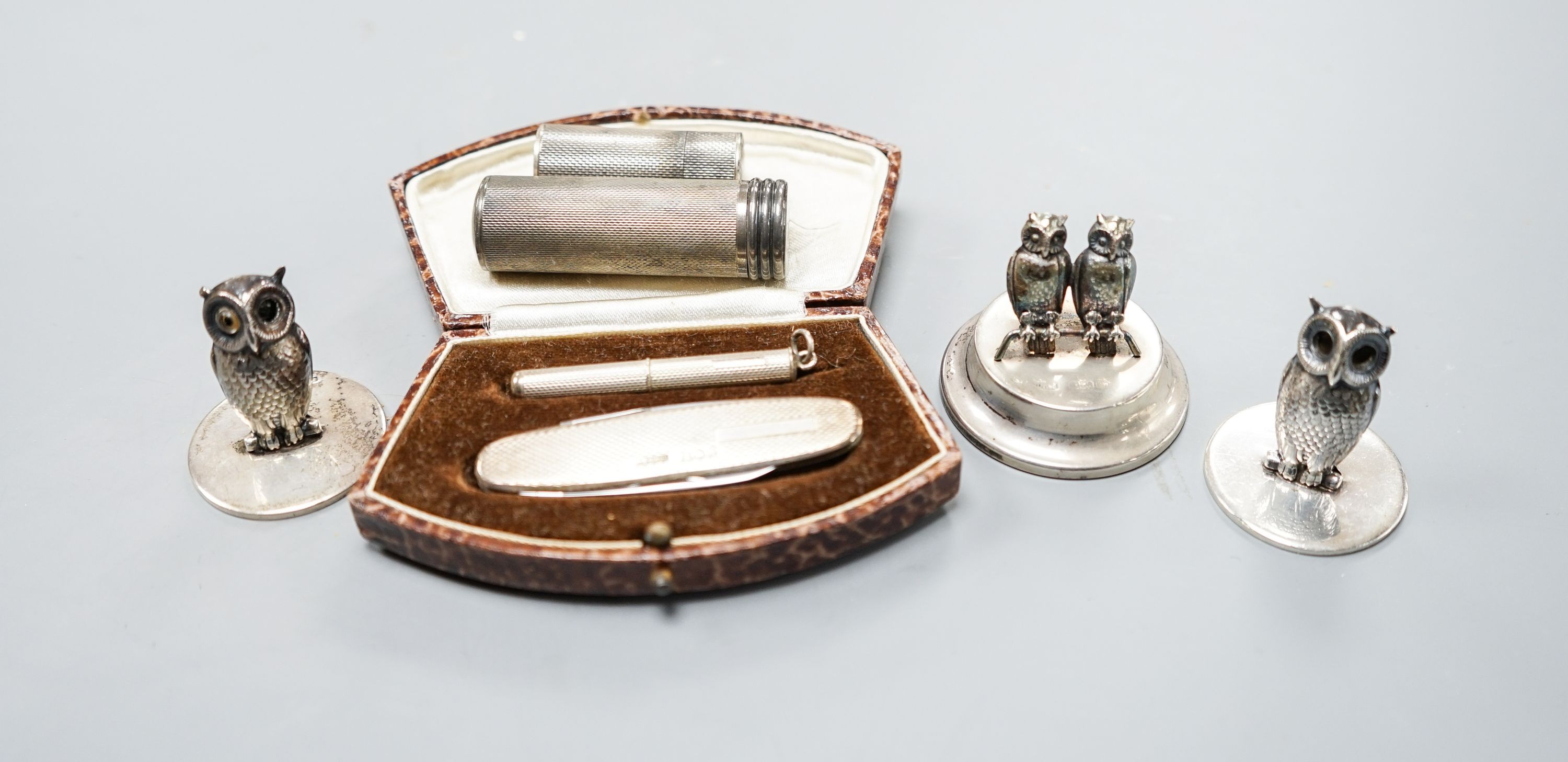 Three silver 'owl' menu holders, including a pair by Samson Mordan & Co, London, 1926, 30mm an engine-turned silver penknife and toothpick set (cased) and two silver cylindrical containers.
